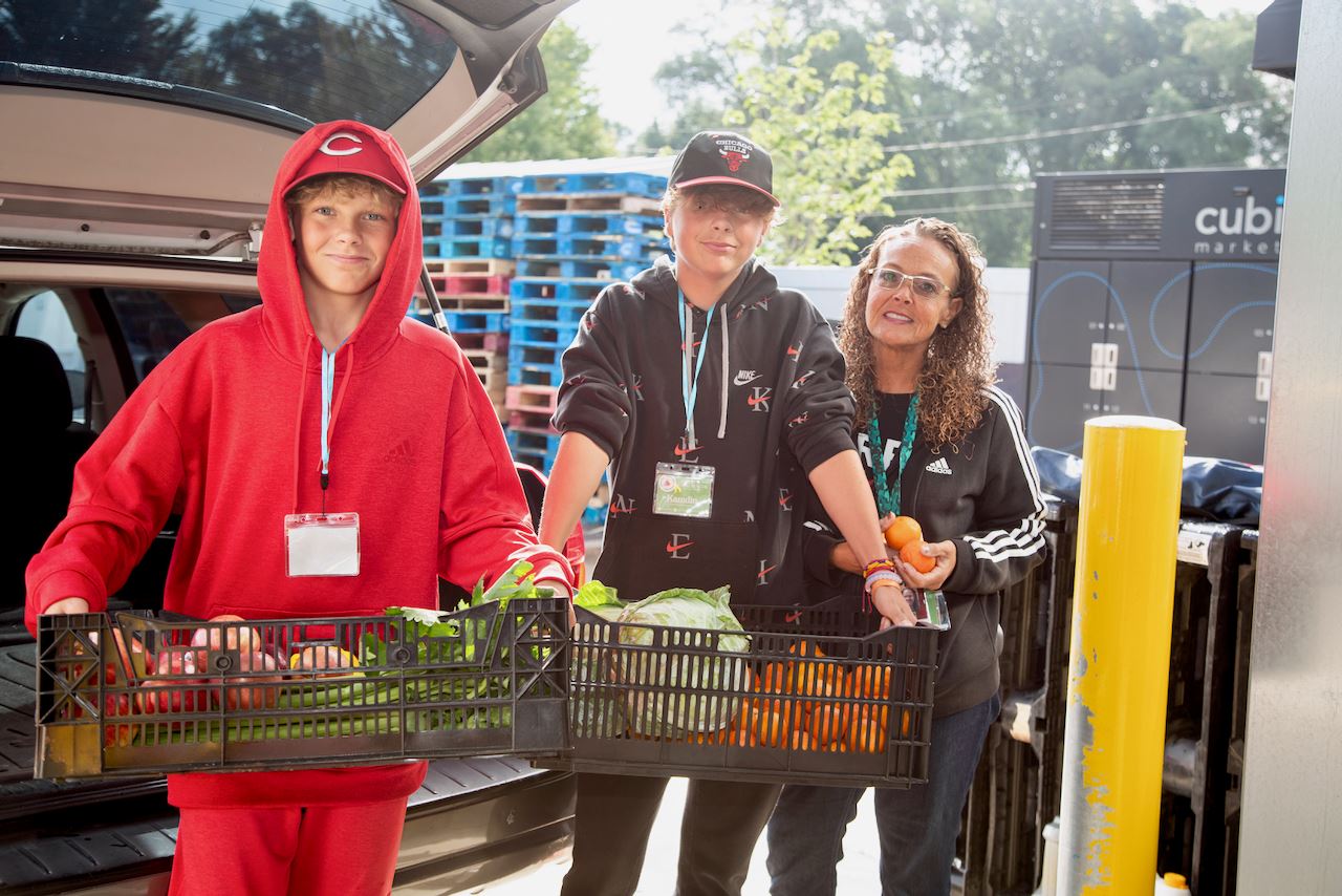 3 youth holding crate of donated fresh food