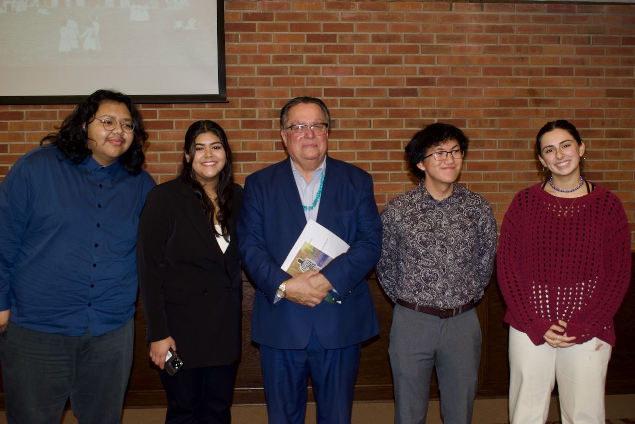 Group of 5 people standing against a brick wall