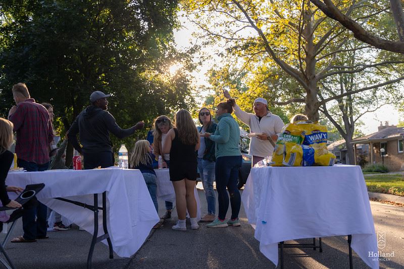 Neighbors clustered around a table of food during a block party.