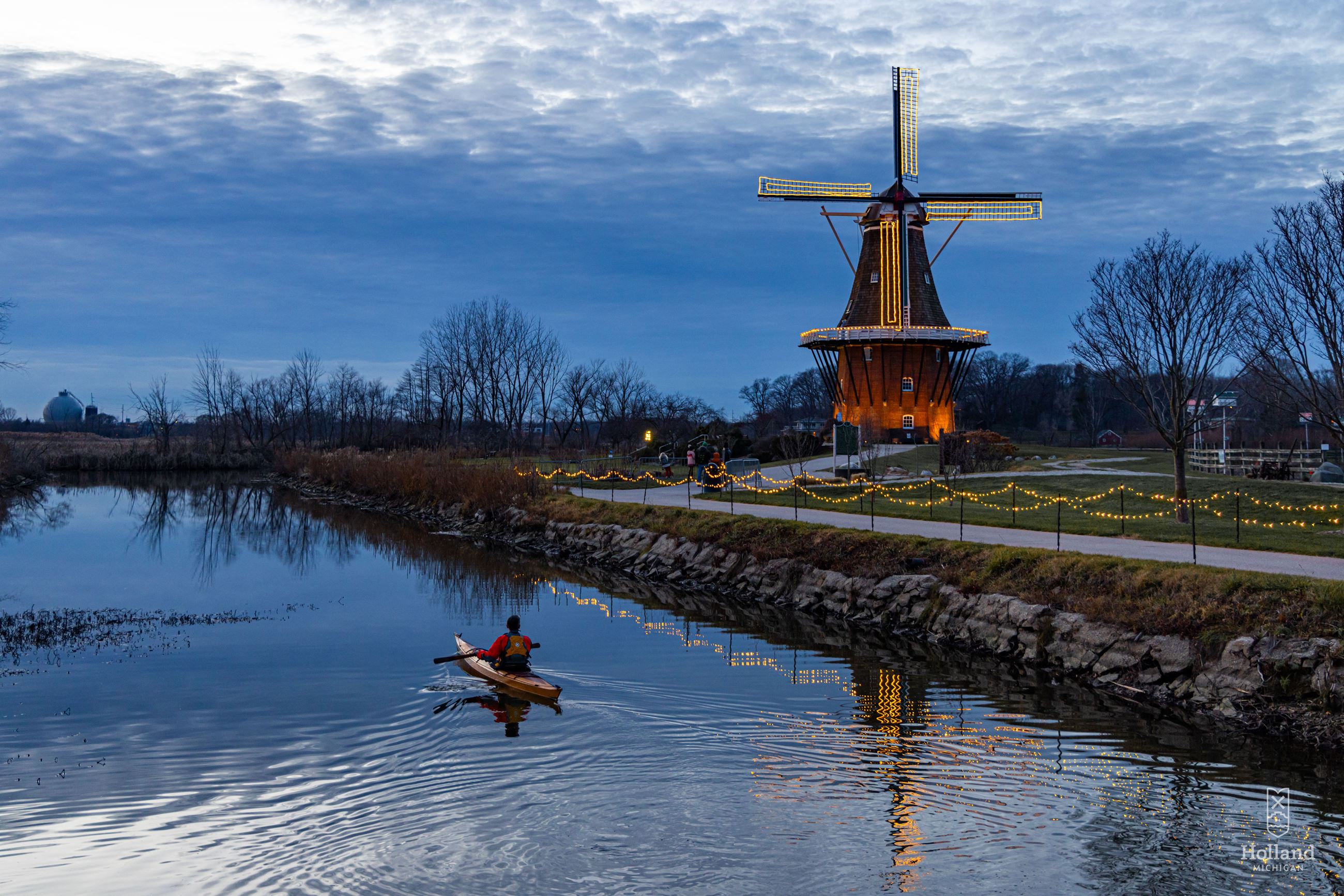 Single Kyaker on river with lit windmill in the background