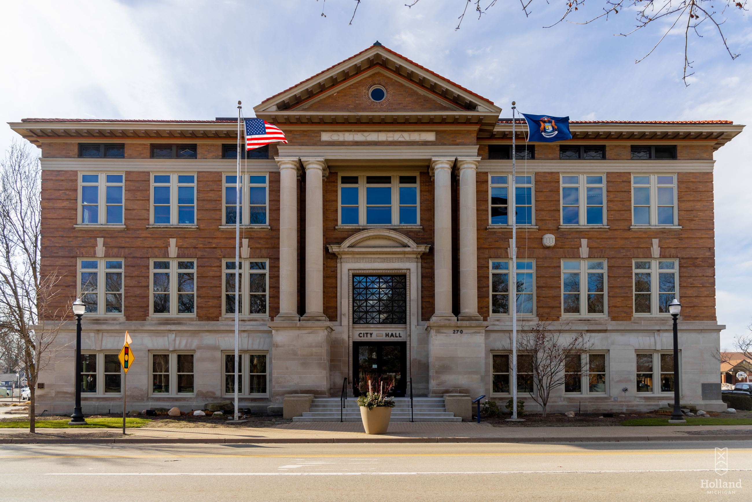 Exterior of Holland City Hall, 3-story brick building with pillars at the entrance