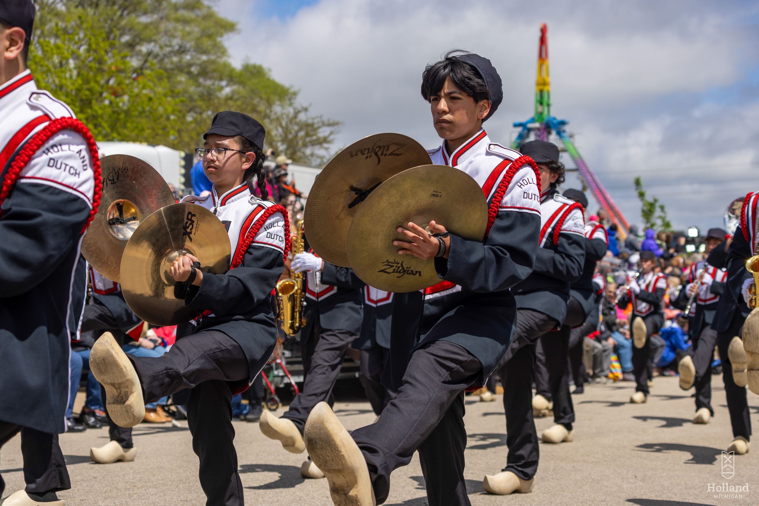 High school students marching in a parade carrying cymbals 