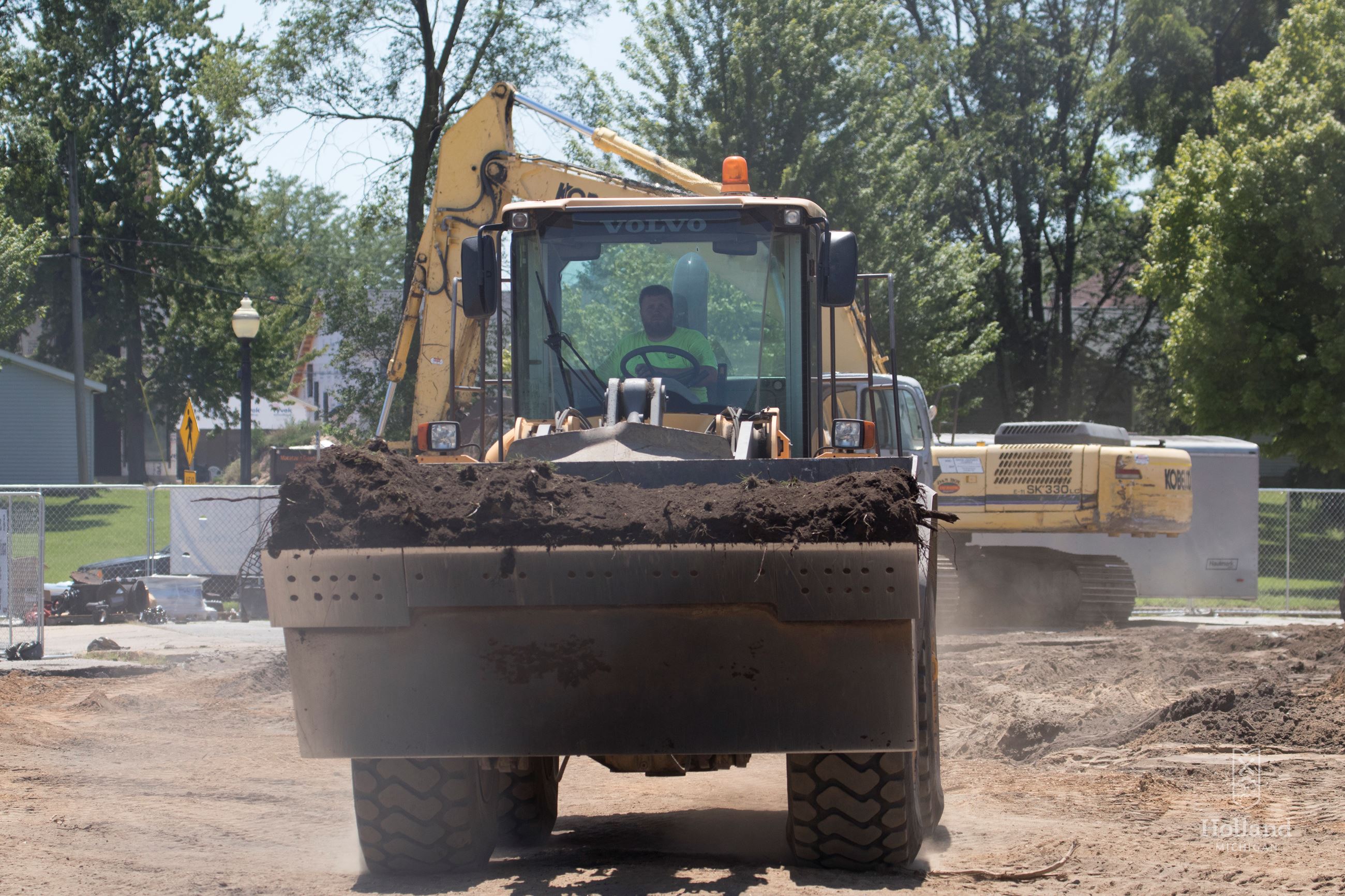 Yellow front loader construction vehicle with driver inside on an unpaved surface