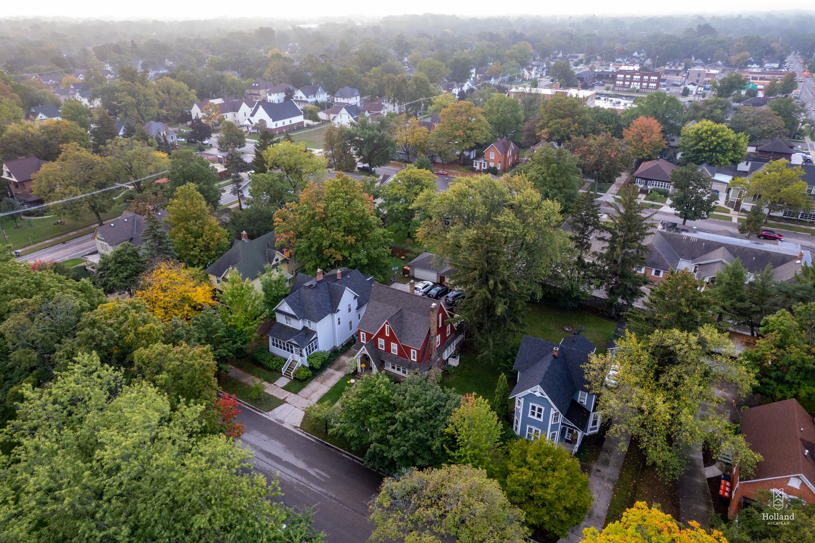 Aerial view of 3 homes, with green trees and sidewalks