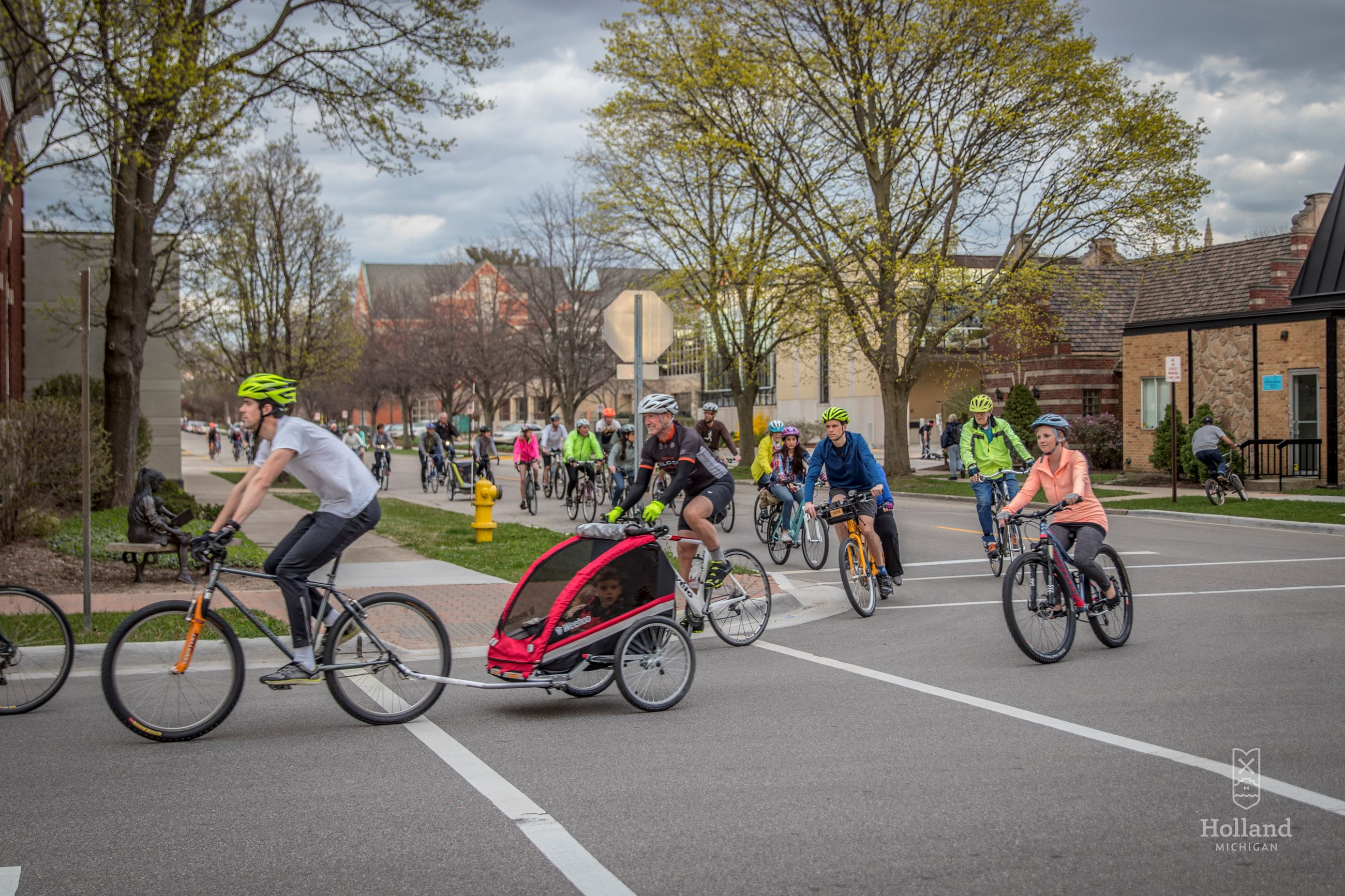 Large group of people riding bikes in a small town city street 