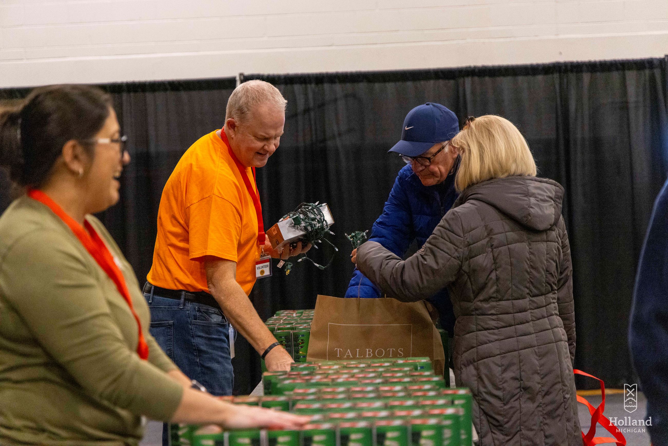 Man handing woman a box of Christmas lights at an Expo
