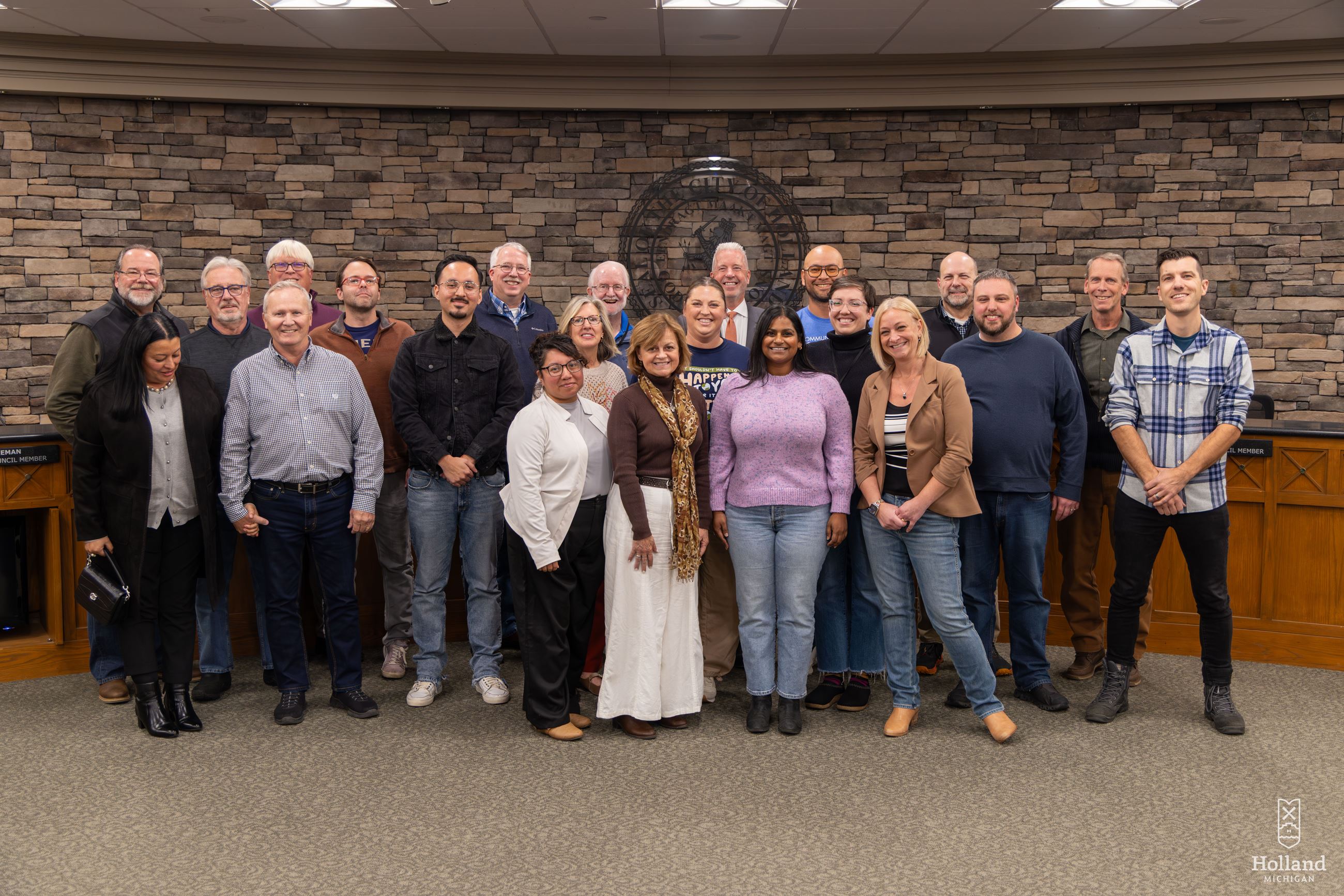 A group of men and women standing in front of the dias of a city council chambers