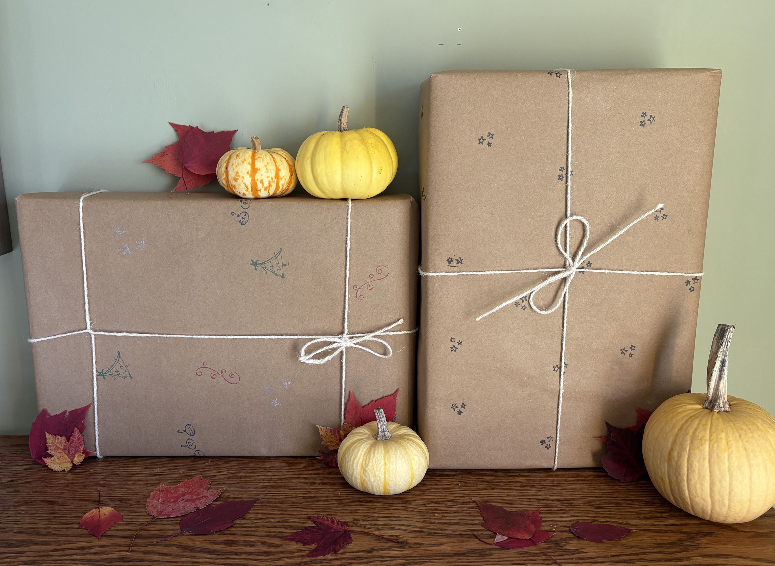 gifts wrapped in brown paper with holiday stamps and twin, with mini pumpkins